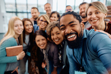 Large group of happy entrepreneurs taking selfie while attending business conference at convection...