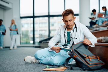 Male student unpacking his backpack while preparing for lecture at medical university.