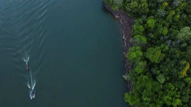 Pan up drone shot flying over the Paran&aacute; river at the Apip&eacute; island in Corrientes, Argentina as two motorboats pass underneath during sunset.