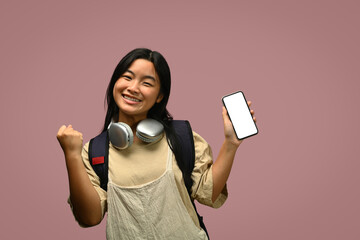 Naklejka premium Teenager schoolgirl with backpack showing smartphone with blank screen on pink background