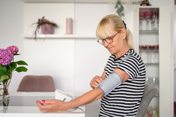 Senior woman measuring blood pressure at home