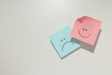 Papers with happy and angry faces, bipolar disorder concept, place for text