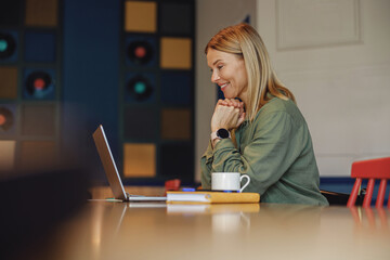 Smiling businesswoman working on laptop in cozy coworking. Distance work concept