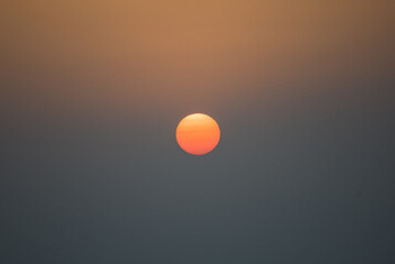 The sun at sunrise. The sun like a ball of fire in the sky.