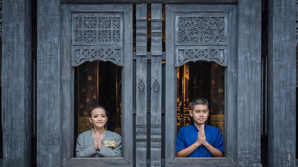 A beautiful pretty Asian Thai woman and handsome man wearing modern traditional Thai dress clothes posted at ancient temples in Chiang Mai Thailand.