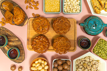 a tasty round moon cakes at mid autumn festival. Flat lay mid autumn festival food and drink on sweet pink background.