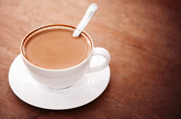 Hot chocolate in white ceramic mug on wooden table.