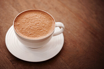 Hot chocolate in white ceramic mug on wooden table.