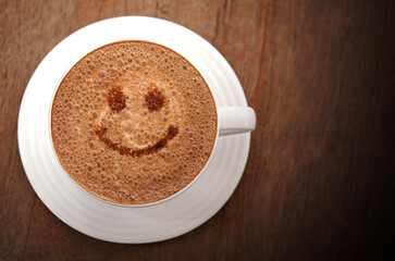 Hot chocolate in white ceramic mug on wooden table.