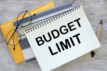 wooden table.yellow notepad and open notebook with text budget limit