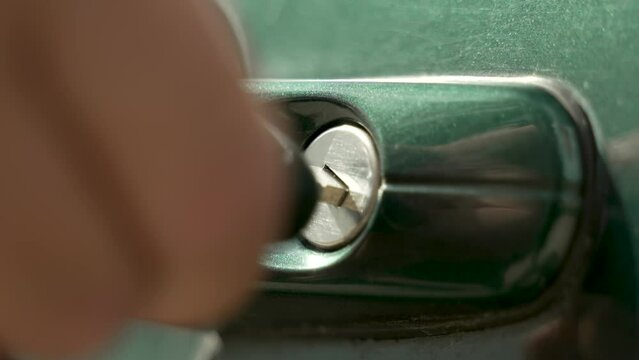 automotive theme
close-up of the keyhole of the central car lock of a green car
the owner man approaches the car and inserts the keys, turns them and opens the door
checking the alarm system 