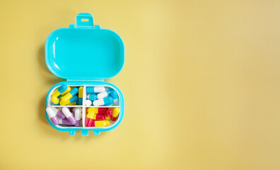 Daily pill box with medical pills isolated on yellow background with copy space for your text. Top...