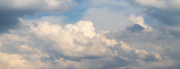 Dramatic sky with white fluffy clouds illuminated by the evening sun