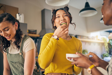 Women, friends and eating healthy food in home for bonding, nutrition and happy lunch together. Fruit diet, sharing and wellness, fresh summer friendship and girls in kitchen with smile at party. - Powered by Adobe