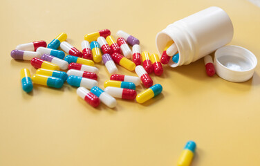 Pharmaceutical medicine pills, tablets and capsules on colourful yellow background. Top view. Flat...