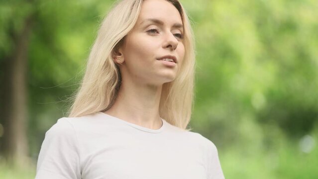 Portrait of confident young blond woman looking ahead and exhaling fresh air taking deep breath and reducing stress after work at park Successful beautiful female resting for peaceful mind outdoors