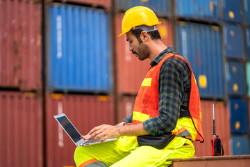 Professional engineer container cargo foreman in helmets working and using laptop checking stock into container for loading.logistic transport and business industry export