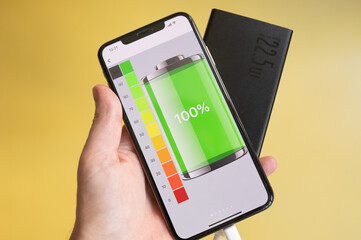 Power Bank charges your smartphone on a yellow background. Universal external battery for gadgets...