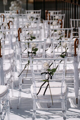Decorated wedding ceremony with transparent chairs white roses and white umbrellas