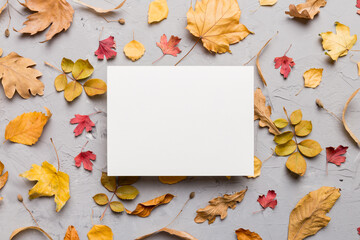 Autumn composition with paper blank and dried leaves on table. Flat lay, top view, copy space