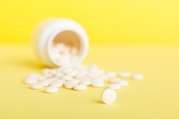 Medicine bottle and white pills spilled on a light background. Medicines and prescription pills flat lay background. White medical pills and tablets spilling out of a drug bottle