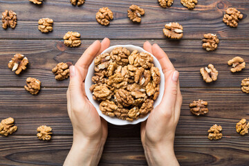 Woman hands holding a wooden bowl with walnut nuts. Healthy food and snack. Vegetarian snacks of different nuts