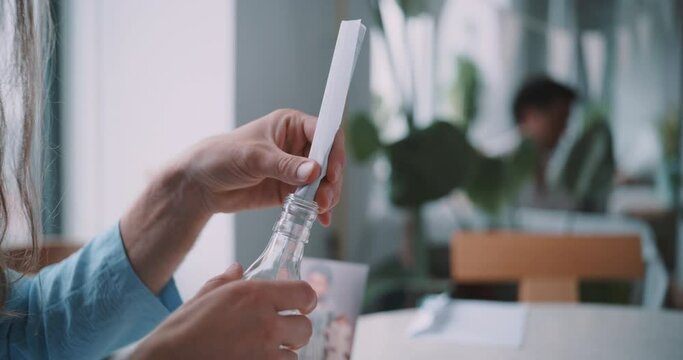 Hands of a man trying to introduce a letter in a bottle. 