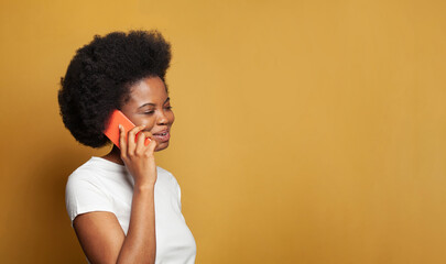 Happy woman with smartphone against bright yellow studio wall banner background