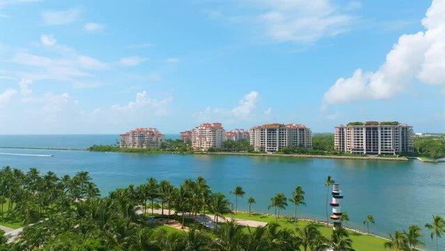 Picturesque sight on South Pointe Park with palm trees, lighthouse and stunning area for recreation. View from drone on Fisher Island with row of stunning high-rise residences