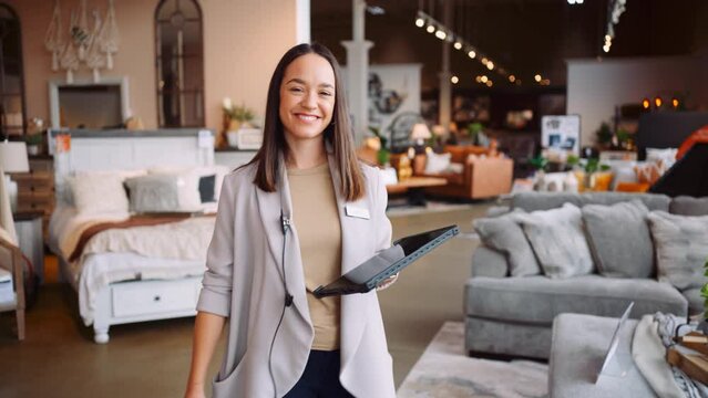 A Young Professional Mom Well Dressed Female Manager Sales Business Woman Walks Towards the Camera Smiling Glancing Down Happy at Work Tablet Technology Tracking Device in a Furniture Store Summer Day