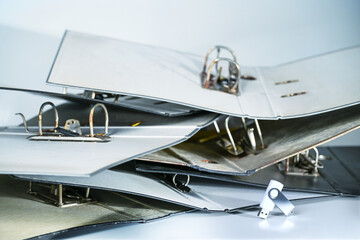 Heap of empty old file folders or ring binders and a small usb-stick, concept for space-saving...