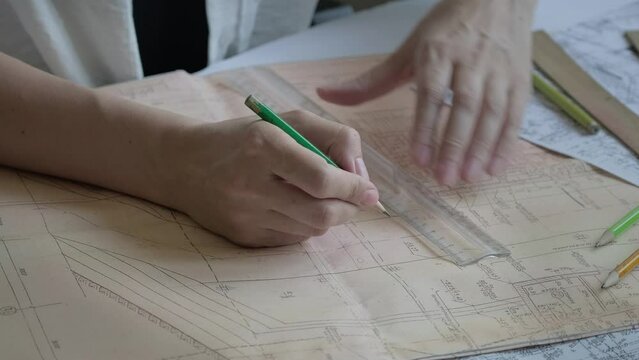 Architect using ruler and pencil to make blueprints on old paper. Engineer works with blueprints. Drafting, drawing lines on the old large format paper. Building diagram