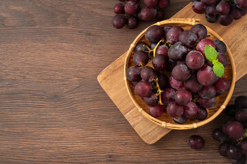 Delicious bunch of grapes fruit in a plate on wooden table background.