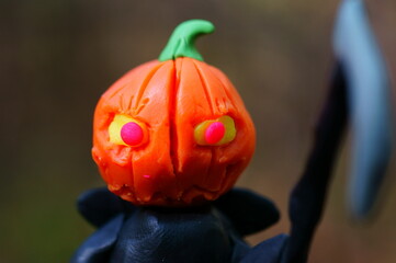 A ghost figurine with a pumpkin on its head and a scythe. Halloween decorations.