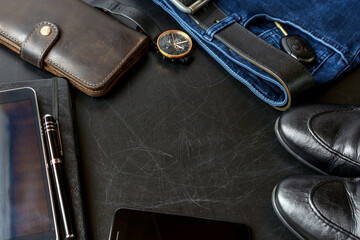 Men's accessories (notebook, pen, phone, shoes, wrist watches, wallet, purse, belt, jeans, pants, shoes) on a black board. - 633702079
