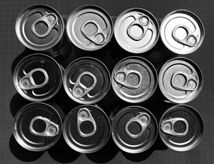 arranged tin cans with opener from above in black and white