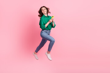 Full body profile photo of energetic pretty lady jump rush empty space use smart phone isolated on pink color background