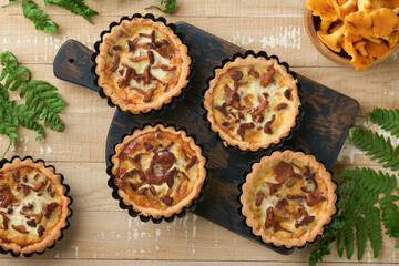 Savory hands pie with chanterelle mushrooms, cream and cheese on cutting board on rustic old white wooden table background. Homemade tarts with seasonal chanterelle mushrooms. Rustic style. Top view.
