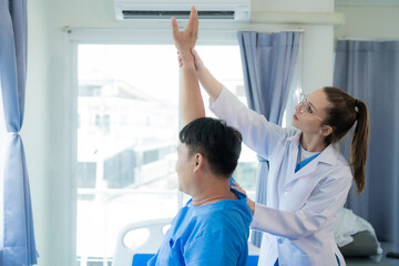 Fototapeta premium Female doctor doing physiotherapy stretching male patient's shoulder, doctor doing osteoporosis treatment exercise in modern clinic.