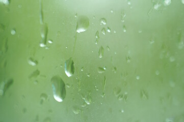 Drops on the window pane. Background image. Green tone.