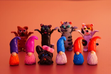 Figurines of colorful dwarfs, seals and dogs made of plasticine. Color background. Festive mood.