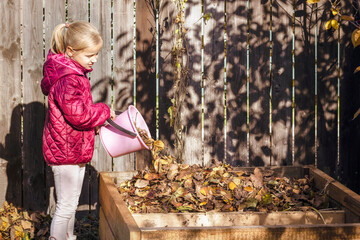 Composting  Autumn Leaves. Little Girl Child Throwing Waste Fall Leaves into Compost Heap. Eco...