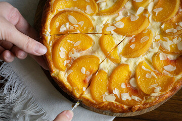 Casserole pie of cottage cheese with peaches. Woman cutting the pie