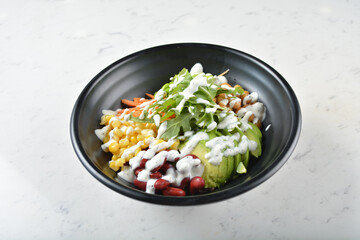 colourful healthy bowl assorted salad, vegetables, avocado, corn, bean, carrot rainbow salad dressing sauce on white marble table background chef cook healthy poke bowl halal vegan food menu