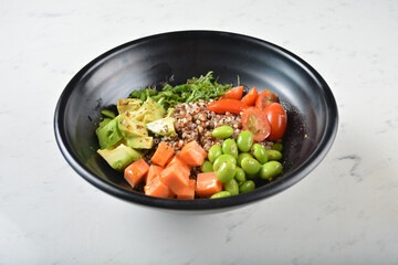 trio quinoa grain salad bowl with avocado, tomato, pea bean, carrot and brown rice in black bowl on...