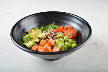 trio quinoa grain salad bowl with avocado, tomato, pea bean, carrot and brown rice in black bowl on white marble table background chef cook healthy poke bowl halal vegan food menu