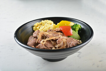 stir fried bbq bulgogi beef rice bowl with scrambled eggs and fried vegetable salad in black bowl on white marble table background chef cook healthy poke protein bowl halal vegan food menu