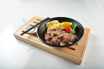 stir fried bbq bulgogi beef rice bowl with scrambled eggs and fried vegetable salad in black bowl on white marble table background chef cook healthy poke protein bowl halal vegan food menu