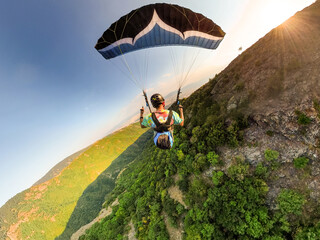 Extreme paraglider pilot flying over Bulgarian mountains, adventure concept.