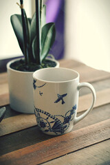 coffee cup on a wood table with plant